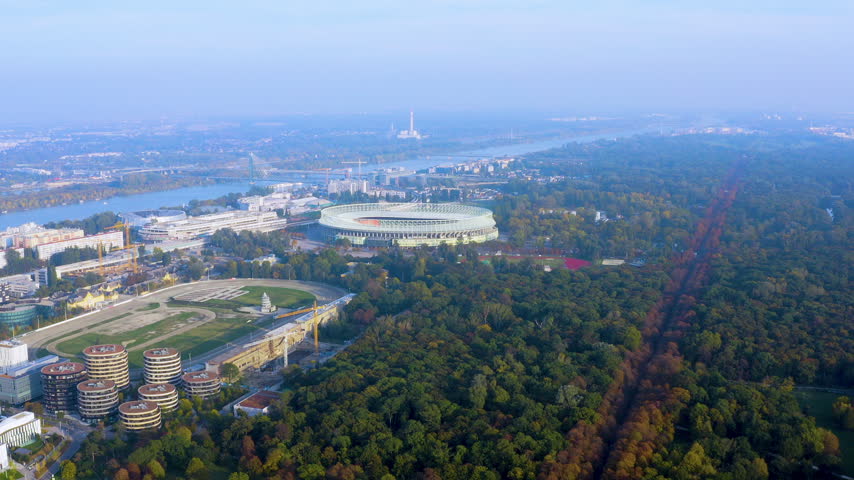 Aerial drone view of the Ernst Happel Stadium in Vienna with the Prater park and Hauptallee in autumn colors, Krieau trotting track, residential towers and the Danube River, Austria.