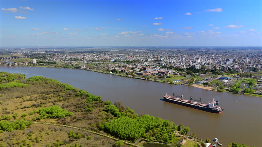 Cargo ship sailing past the cityscape of Zarate along the Parana River in Buenos Aires Province, Argentina.