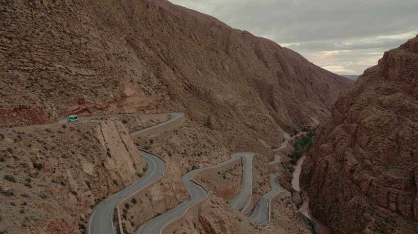 Winding mountain road through Dades Gorges in Morocco. Breathtaking aerial view of a serpentine road carved into the rock face. Stunning landscape of canyons and cliffs in vibrant sunset hues.