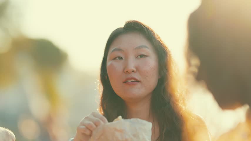 Friends enjoying food together at sunset in an outdoor location
