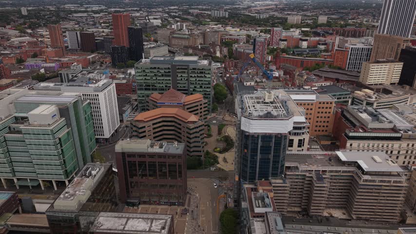 Smooth lateral drone flight across Birmingham city centre revealing dense urban architecture, office buildings, modern developments and traditional brick structures across the city.