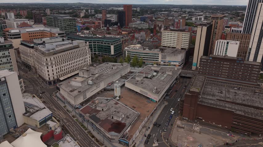 Aerial drone view of Birmingham city centre revealing contrasting architectural styles, from large office blocks and urban roads to dense historic brick buildings and modern developments.