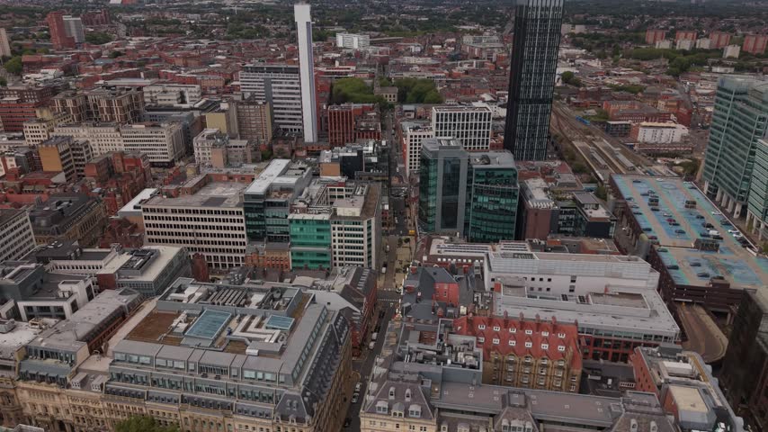 Top-down aerial drone view over Birmingham city centre showing a long urban street surrounded by dense architecture, modern high-rise buildings, offices and traditional brick buildings.