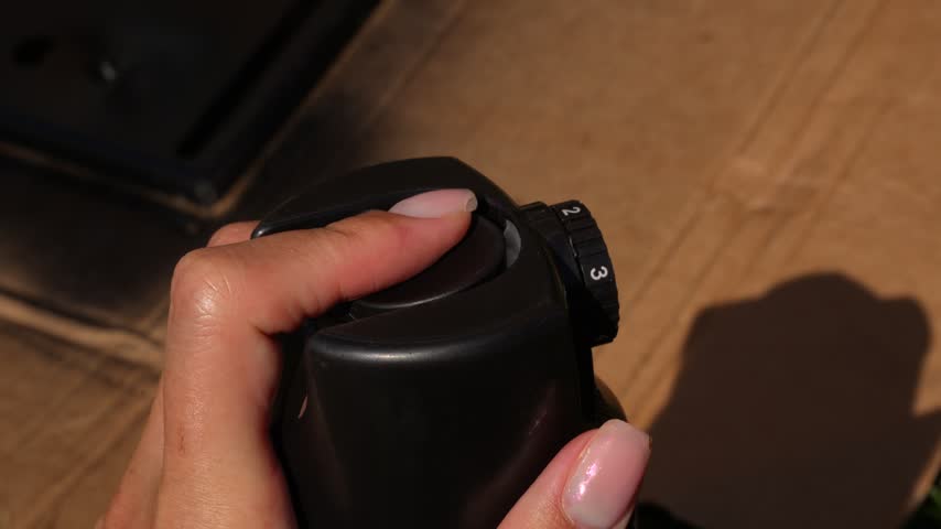 Video of a hand holding a spray paint can, spraying paint onto a part placed on cardboard, DIY spray painting process in action