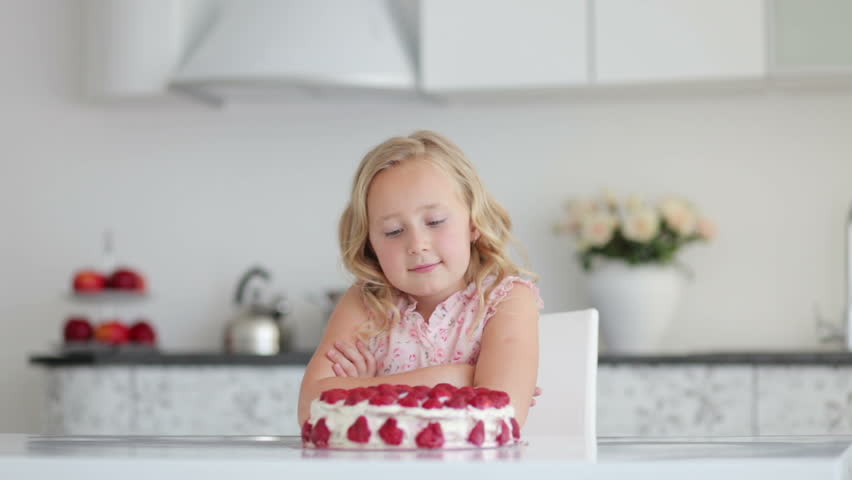 Sweet girl looking at a big cake and smiling
