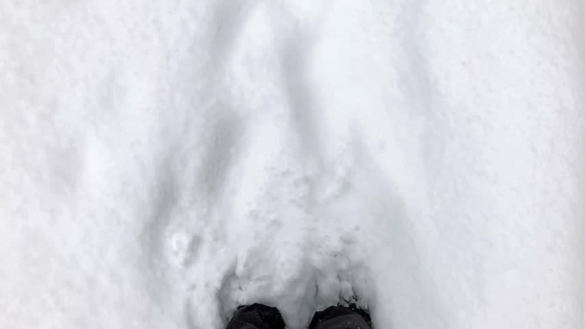 Footprints made in untouched snow reveal depth along a snowy pathway with close-up details of the soft texture and the surrounding winter landscape with clear visibility