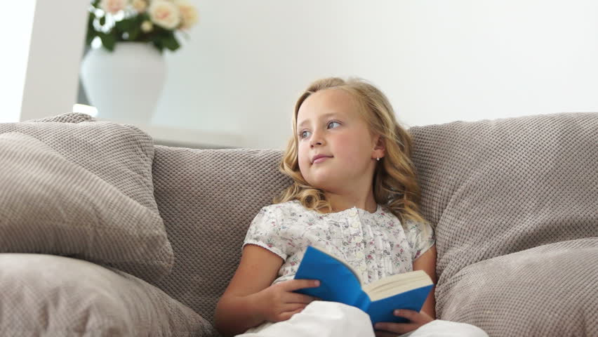 Little girl reading a book on the couch
