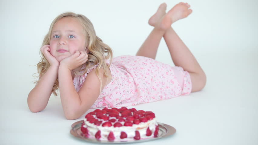 Sweet girl lying and admired strawberry cake
