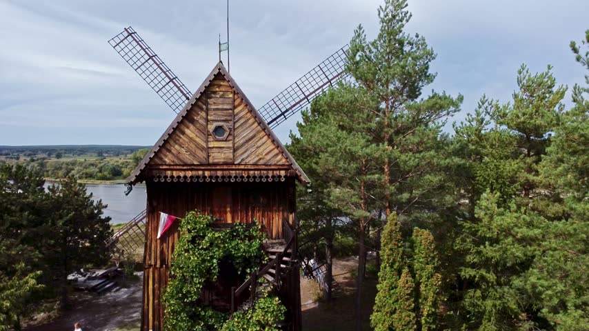Majestic wooden windmill standing among pine trees near a river in kazimierz dolny, poland. Rural landscape showcasing traditional architecture. Kazimierz dolny, poland