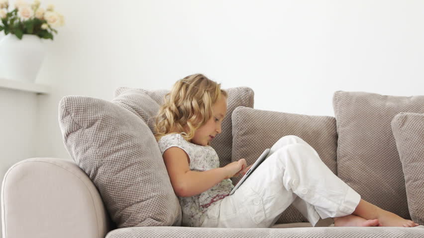 Little girl resting on couch with tablet pc
