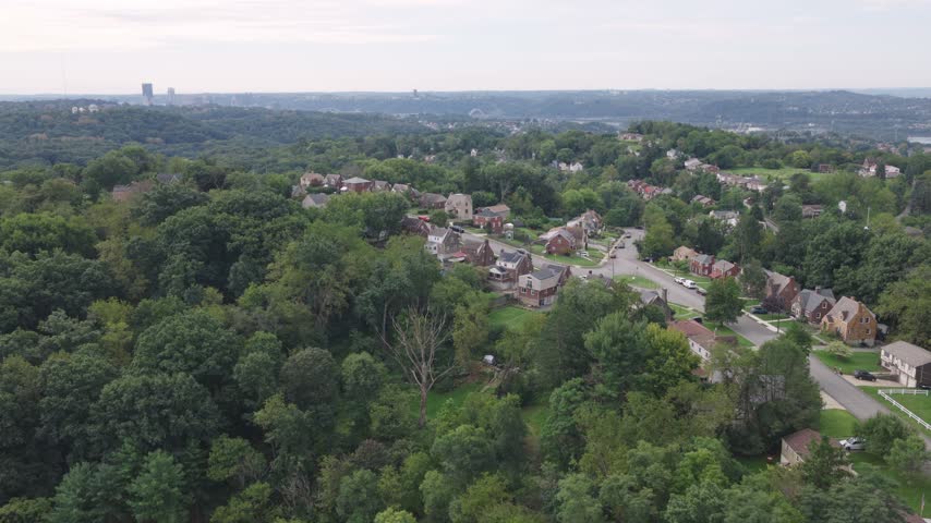 Drone aerial above homes, houses, and suburb in north side hills of Pittsburgh, PA in Perry North Observatory and Summer Hill with cars, streets, trees, and hilly landscape of western Pennsylvania 4k