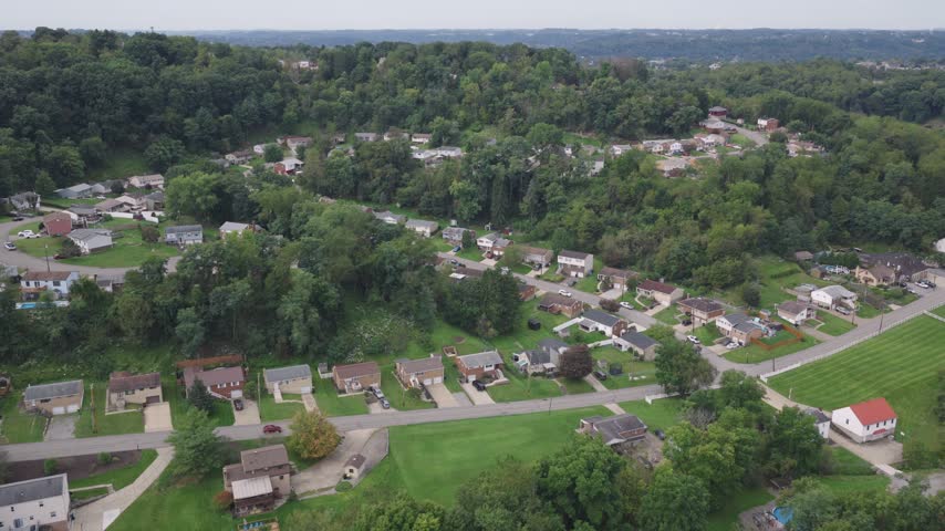 Drone aerial above homes, houses, and suburb in north side hills of Pittsburgh, PA in Perry North Observatory and Summer Hill with cars, streets, trees, and hilly landscape of western Pennsylvania 4k