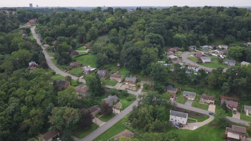 Drone aerial above homes, houses, and suburb in north side hills of Pittsburgh, PA in Perry North Observatory and Summer Hill with cars, streets, trees, and hilly landscape of western Pennsylvania 4k