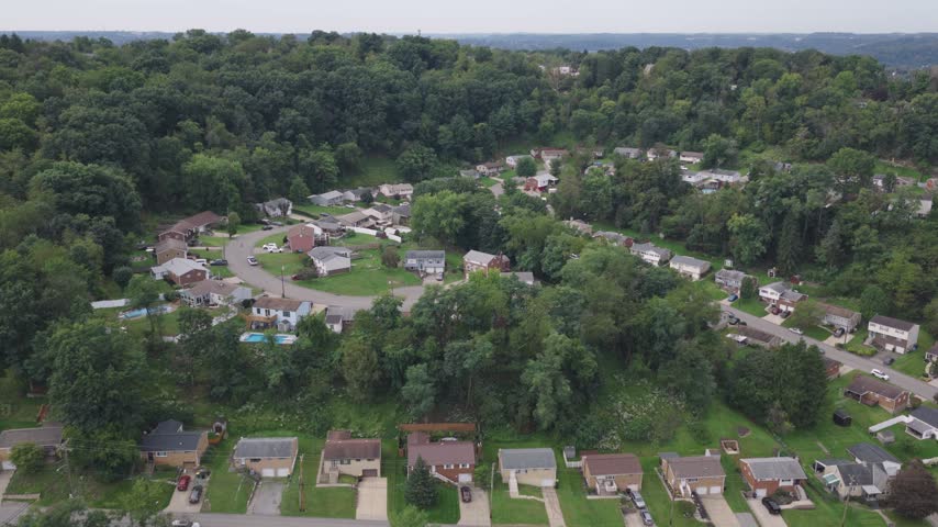 Drone aerial above homes, houses, and suburb in north side hills of Pittsburgh, PA in Perry North Observatory and Summer Hill with cars, streets, trees, and hilly landscape of western Pennsylvania 4k