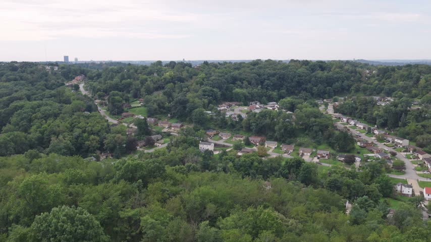 Drone aerial above homes, houses, and suburb in north side hills of Pittsburgh, PA in Perry North Observatory and Summer Hill with cars, streets, trees, and hilly landscape of western Pennsylvania 4k