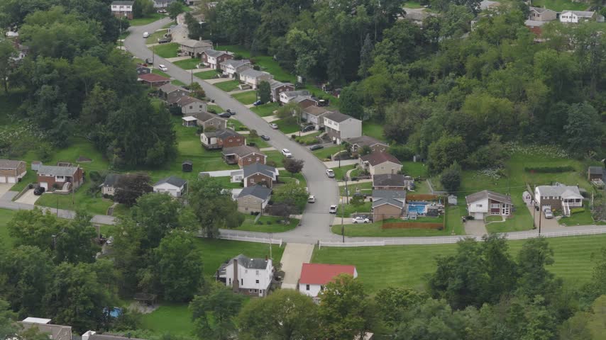 Drone aerial above homes, houses, and suburb in north side hills of Pittsburgh, PA in Perry North Observatory and Summer Hill with cars, streets, trees, and hilly landscape of western Pennsylvania 4k