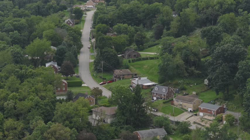 Drone aerial above homes, houses, and suburb in north side hills of Pittsburgh, PA in Perry North Observatory and Summer Hill with cars, streets, trees, and hilly landscape of western Pennsylvania 4k