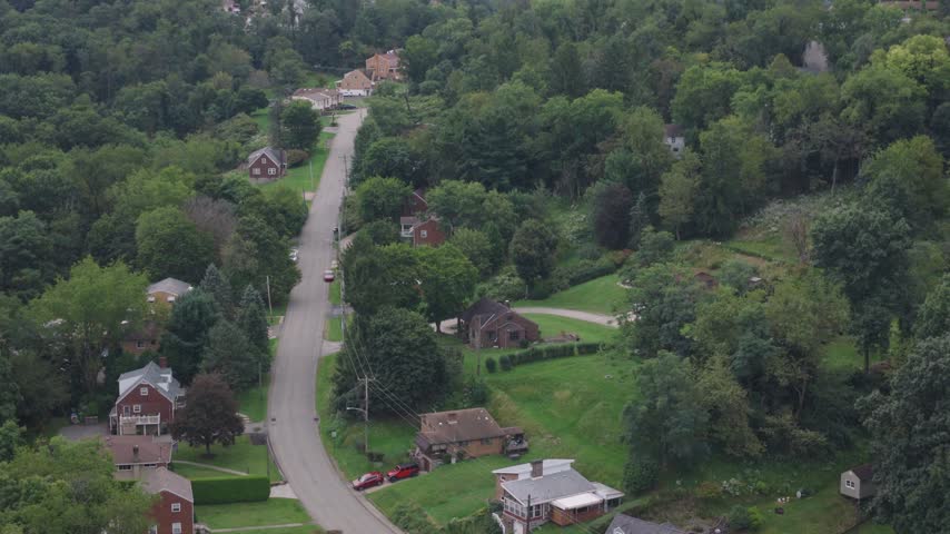 Drone aerial above homes, houses, and suburb in north side hills of Pittsburgh, PA in Perry North Observatory and Summer Hill with cars, streets, trees, and hilly landscape of western Pennsylvania 4k