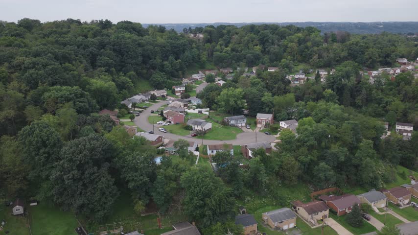 Drone aerial above homes, houses, and suburb in north side hills of Pittsburgh, PA in Perry North Observatory and Summer Hill with cars, streets, trees, and hilly landscape of western Pennsylvania 4k