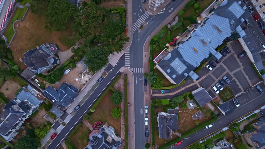 Street intersection, cars, and residential architecture in the coastal town of Saint-Lunaire, France. Aerial top-down forward