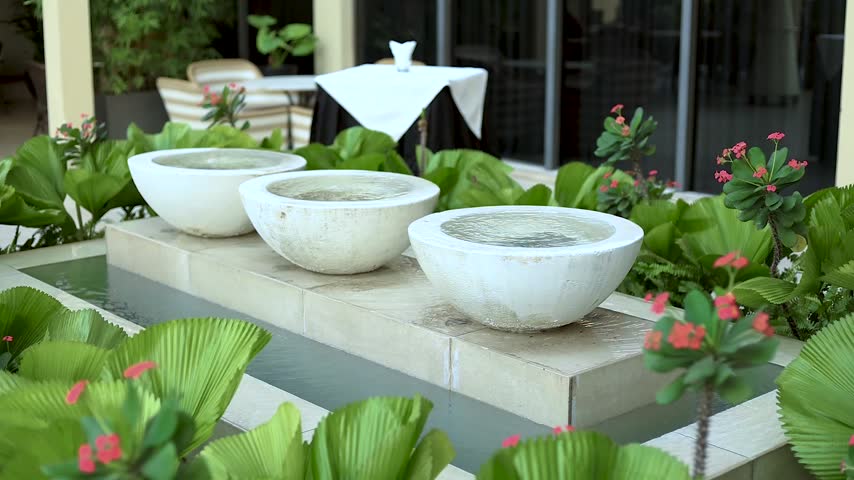 Beautiful artificial water fountain surrounded by colorful flowers in a landscaped garden. 