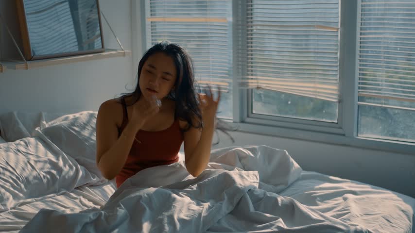 Beautiful asian woman smoothing her hair to prepare lying asleep enjoying healthy good sleep nap. Young woman sleeping well in comfortable cozy fresh bed on soft pillow white linen.