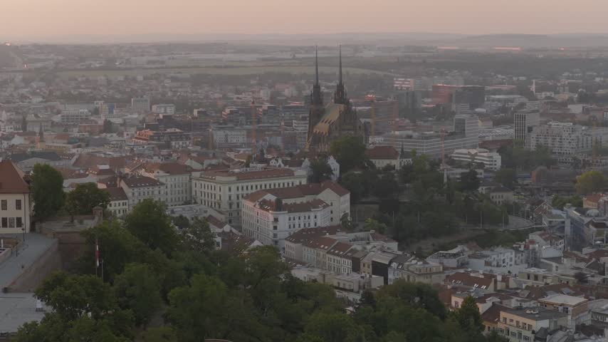 Warm early morning light reveals Brno city skyline and Petrov Cathedral as seen from Špilberk Castle hill.