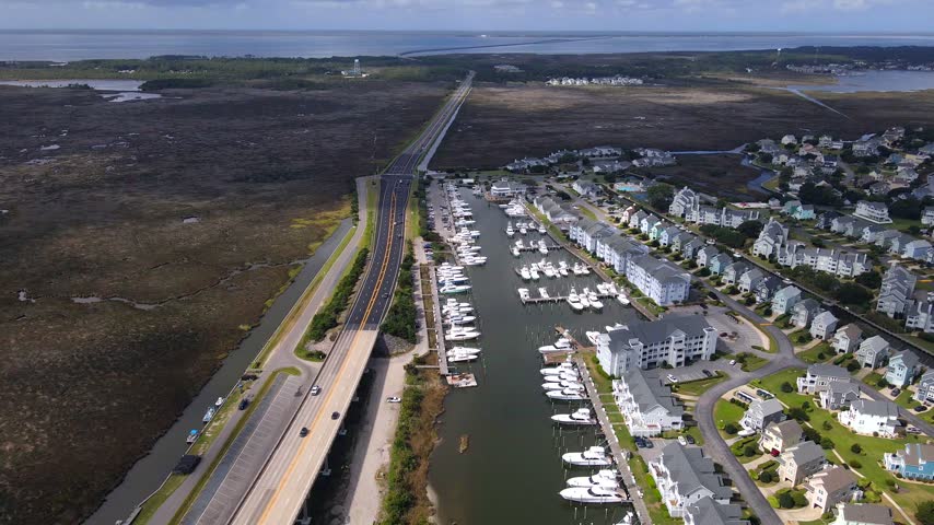 Rows of moored boats line a sheltered marina beside waterfront condominiums in Manteo, NC.