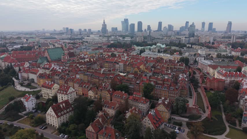 Wide aerial panorama of the Warsaw Old Town featuring historic tenements and the distant modern skyline. Panning right to left