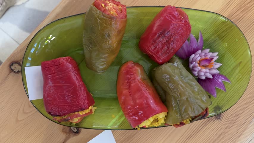 Close-up zoom-in shot of traditional stuffed peppers with rice presented on a plate at a culinary contest in Oliva, Spain.