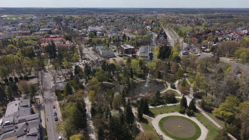 Wide aerial view of the lush Zdrojowy Park with its fountain and town architecture in Ciechocinek, Poland