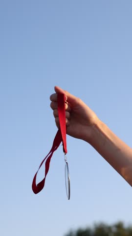 Woman with gold medal outdoors, low angle view. Slow motion effect