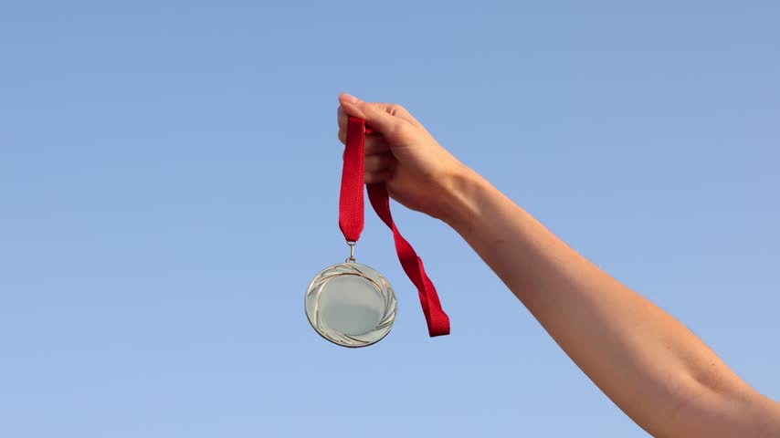 Woman with gold medal outdoors, low angle view. Slow motion effect
