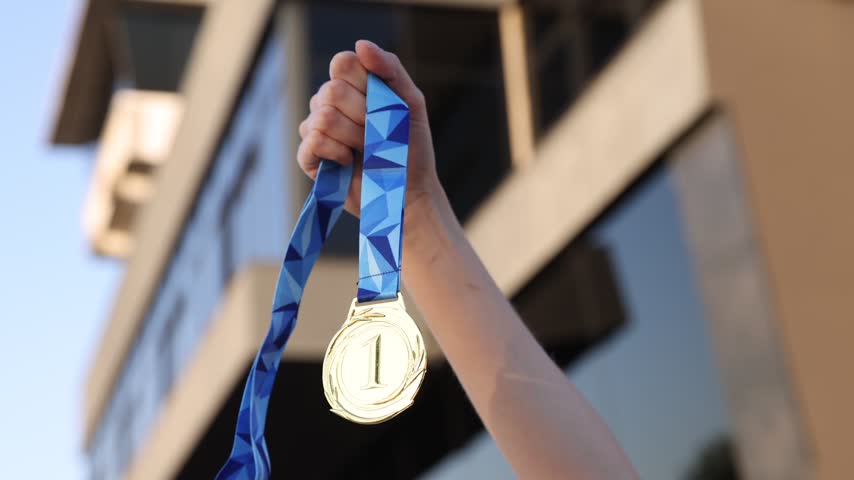 Woman with gold medal outdoors, low angle view. Slow motion effect
