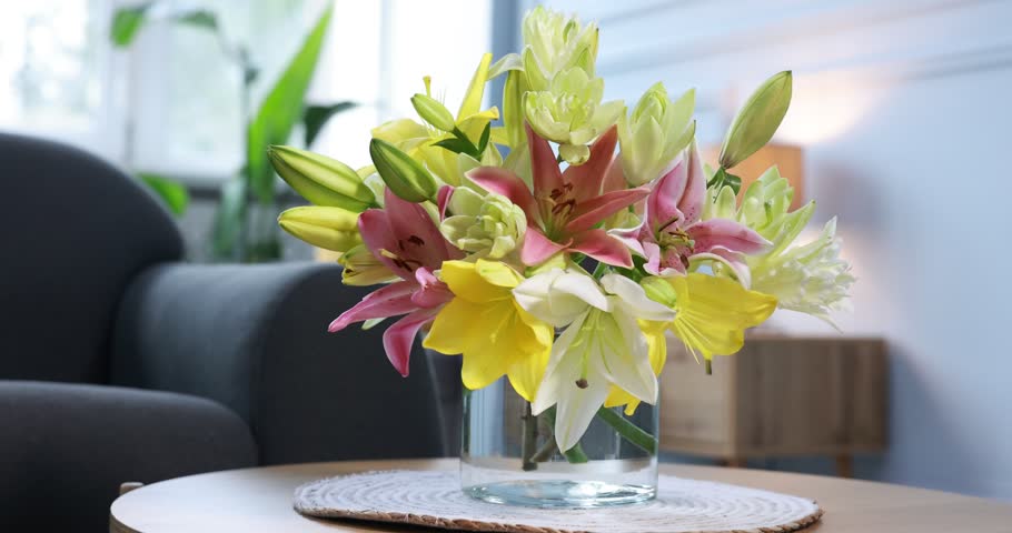 Bouquet of beautiful lilies in vase on table indoors