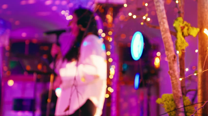 A blurry background enhances a talented singer captivating an audience with vibrant lights at a live show
