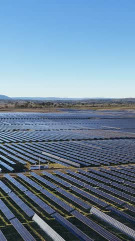 Aerial view over an extensive rural solar panel installation under bright daylight in Australia.