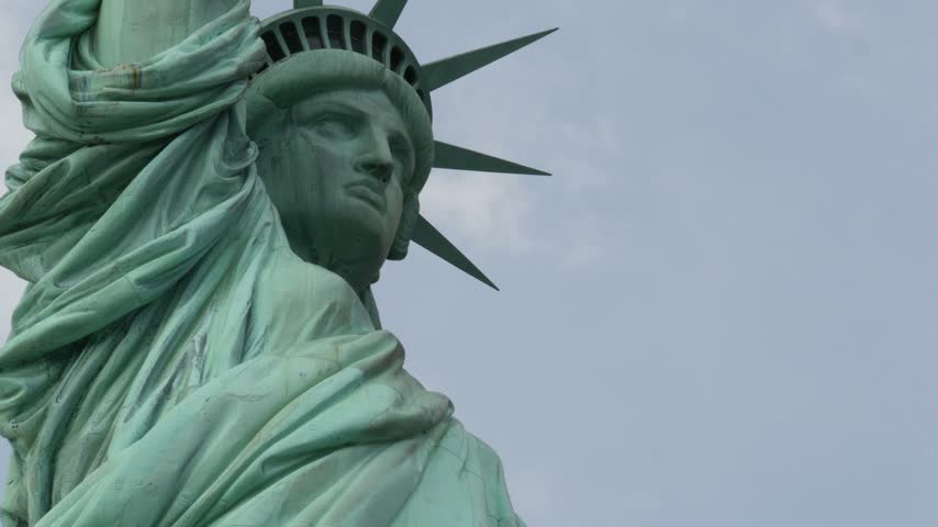 Statue of Liberty on Liberty Island, New York, United States. Blue cooper monument, symbol of democracy and patriotism near Manhattan, NYC USA. Clouds on sky. American independence. Torch and crown.