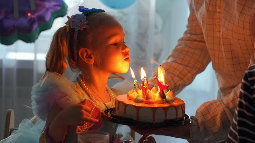 4-year-old girl blowing out candles on her birthday cake