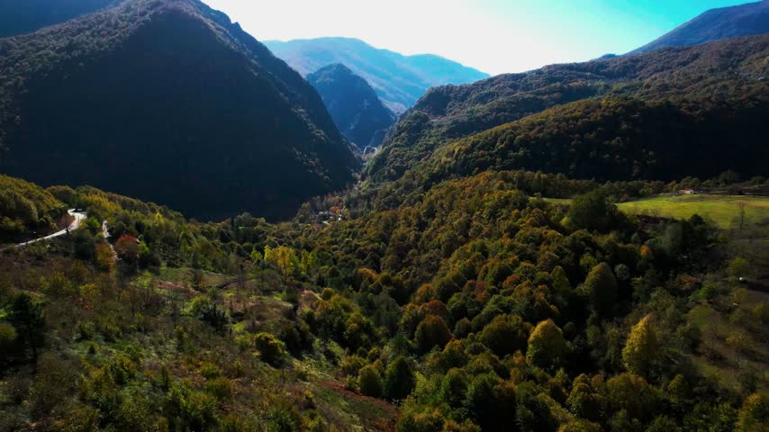 Autumn foliage colors dense woodland surrounding a remote rural mountain settlement.