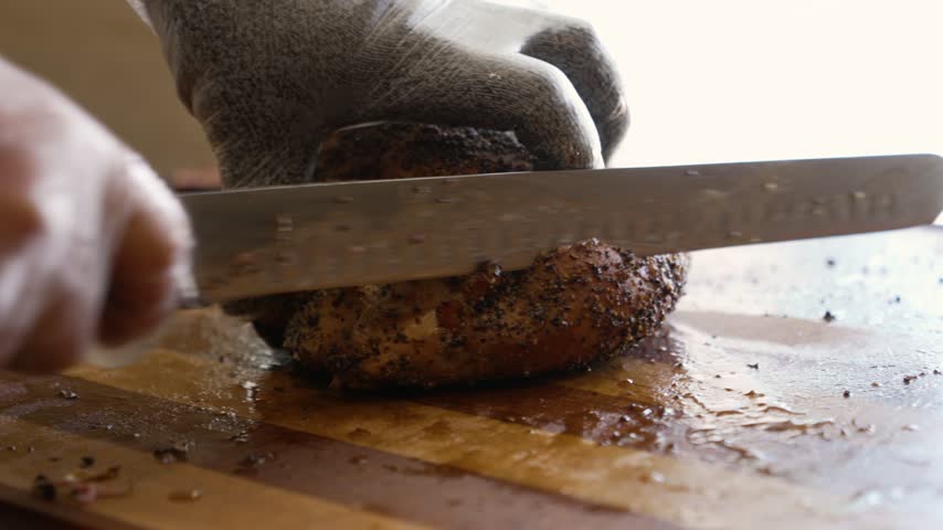 Pitmaster carves juicy, pepper-crusted smoked turkey with precision on a wooden cutting board, slow motion, close up, 4K