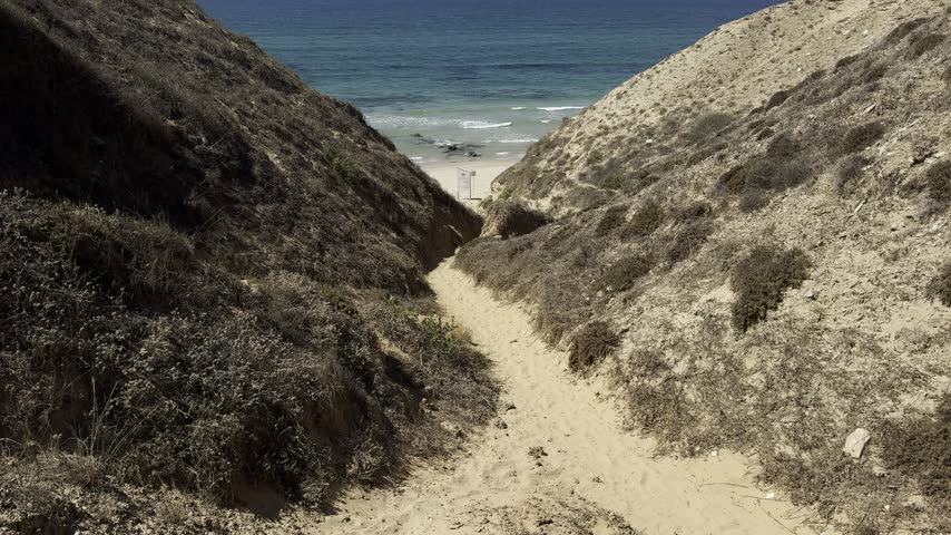 Netanya, Israel. View through rocky formations of Jerusalem limestone across a narrow gorge toward a sandy beach along the Mediterranean coast.