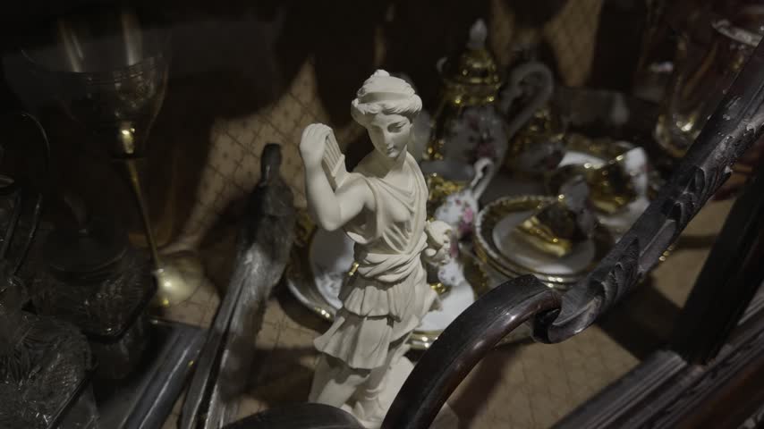 Classical white marble statue of a huntress figure displayed beside a gilded porcelain tea set and candlestick