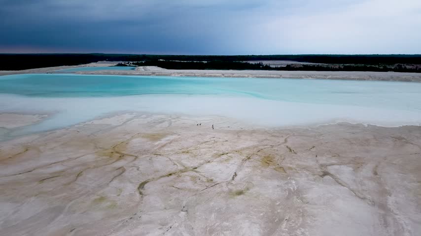 Drone footage reveals pale cracked limestone flats beside turquoise water at the Port Dolomite quarry near Hessel Michigan.