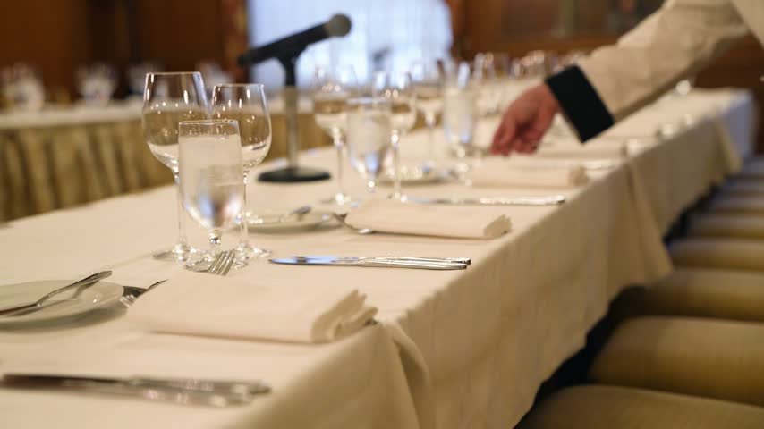 Elegant banquet dinner table setup with sparkling crystal glasses, fine dining plates, and professional catering at a luxury formal event or corporate gala.
