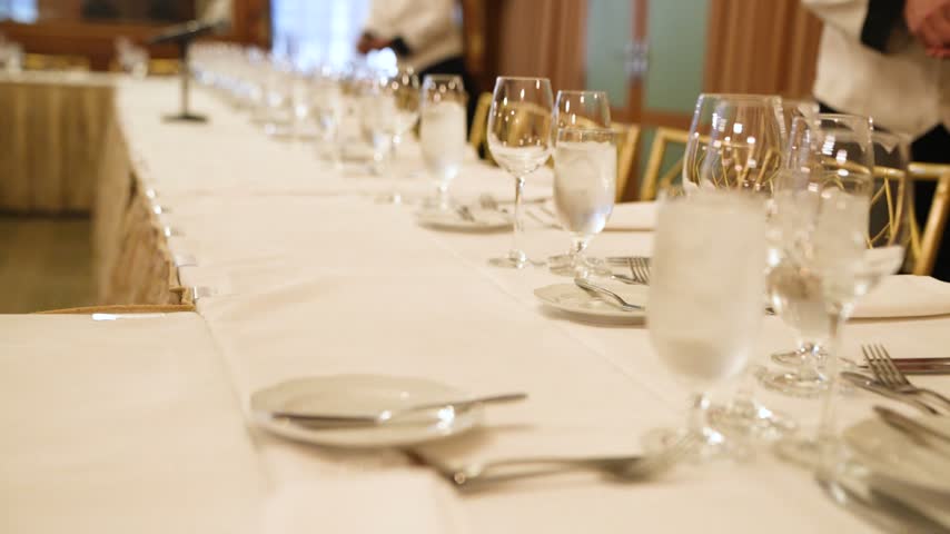 Elegant banquet dinner table setup with sparkling crystal glasses, fine dining plates, and professional catering at a luxury formal event or corporate gala.
