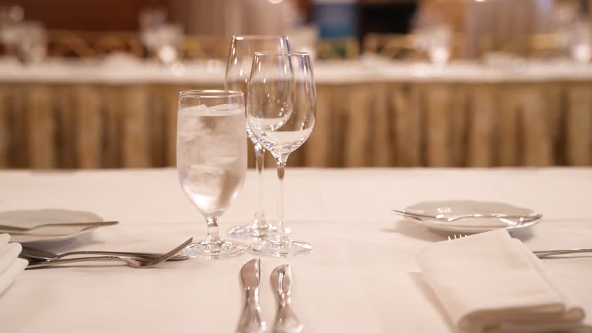 Elegant banquet dinner table setup with sparkling crystal glasses, fine dining plates, and professional catering at a luxury formal event or corporate gala.
