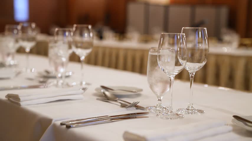 Elegant banquet dinner table setup with sparkling crystal glasses, fine dining plates, and professional catering at a luxury formal event or corporate gala.
