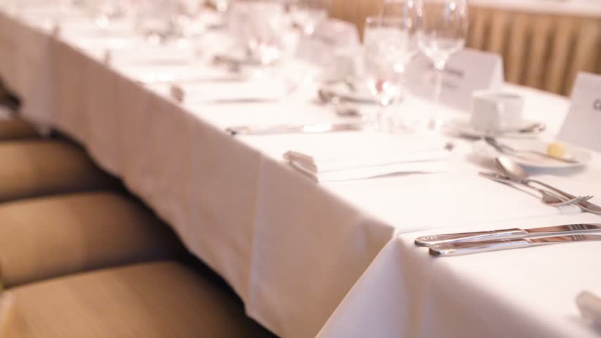 Elegant banquet dinner table setup with sparkling crystal glasses, fine dining plates, and professional catering at a luxury formal event or corporate gala.
