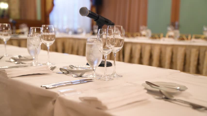 Elegant banquet dinner table setup with sparkling crystal glasses, fine dining plates, and professional catering at a luxury formal event or corporate gala.
